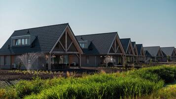 A row of modern, multi-story houses with pitched roofs and large windows, set in a landscaped area with dense greenery.
