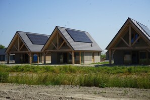 Une rangée de trois maisons modernes, dotées de toits à pignon et de panneaux solaires, se dressant sur un ciel dégagé.