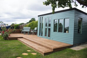A small, light blue wooden building with a deck, a bench, and a table. - Spacious family cottage close to the beach and just a short drive from Edinburgh (Limekilns)