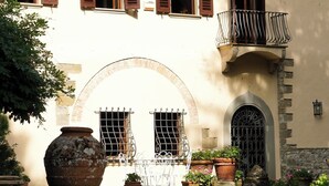 A courtyard with a large terracotta pot, potted plants, and a stone archway.