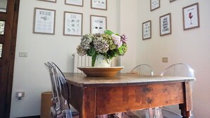 A dining table with a vase of flowers, surrounded by framed botanical illustrations on the wall.