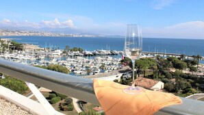 Un port de plaisance avec des bateaux, un verre de vin sur un balcon et, en arrière-plan, une vue sur la ville côtière.