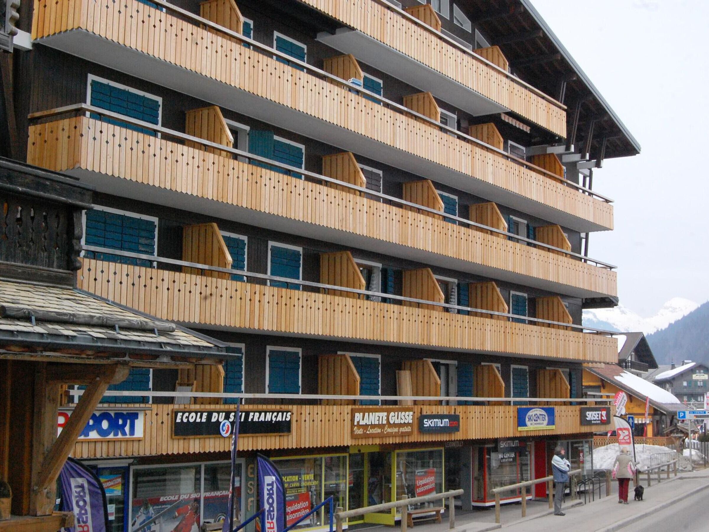 A multi-story hotel with balconies, a ski center, and various shops on the ground floor.