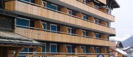 A multi-story hotel with balconies, a ski center, and various shops on the ground floor.