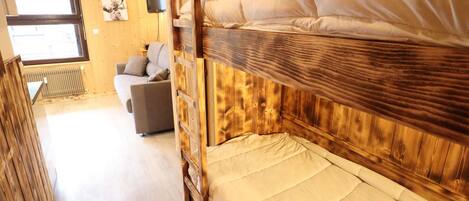 Un intérieur en bois avec un lit superposé, un canapé et un téléviseur.