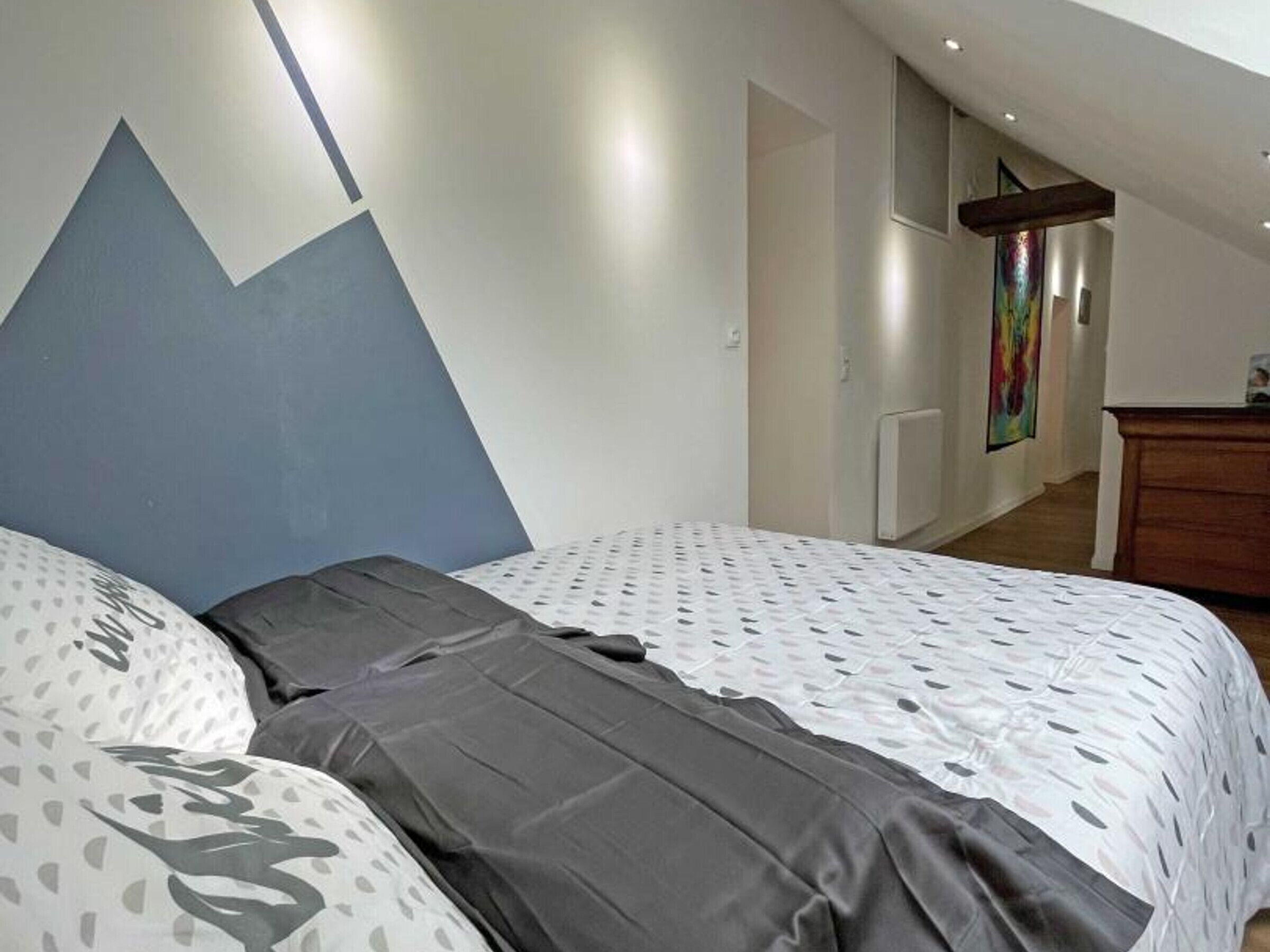 A bedroom with a bed, a dresser, and a painting on the wall.