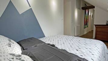 A bedroom with a bed, a dresser, and a painting on the wall.