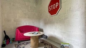 A room with a red chair, a small round table, a stop sign on the wall, and a bottle of wine on the floor. - Old house - 8 guests (Réveillon)