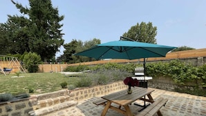 A patio with a wooden table and benches, a green umbrella, and a barbecue grill. - Old house - 8 guests (Réveillon)