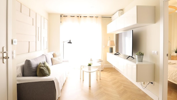 A modern, well-lit room with a sofa, a small table, a TV, and a cabinet.