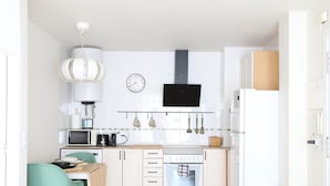 A compact kitchen with a dining area, a clock, and a TV mounted above the stove.
