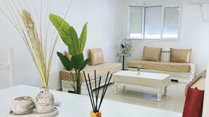 Una sala de estar moderna con un sofá blanco, una mesa de centro y un arreglo decorativo de plantas.