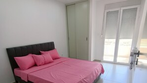 Un dormitorio con cama, armario y puerta corrediza de vidrio al exterior.