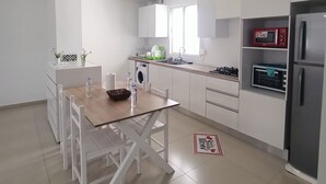 Una cocina moderna con armarios blancos, una mesa de comedor de madera y un horno empotrado.