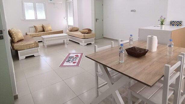 Una sala de estar moderna y bien iluminada con un juego de sofá, una mesa de comedor con sillas y una zona de cocina.