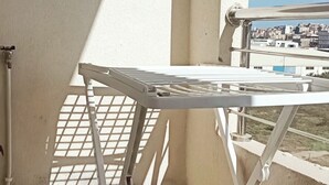 Un tendedero metálico blanco en un balcón con vista a la ciudad.