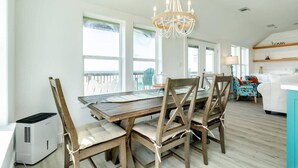 Un comedor con una mesa y sillas de madera, una lámpara de araña y vistas al exterior.