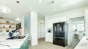 Una cocina moderna con armarios blancos, un refrigerador negro y una isla de mármol.