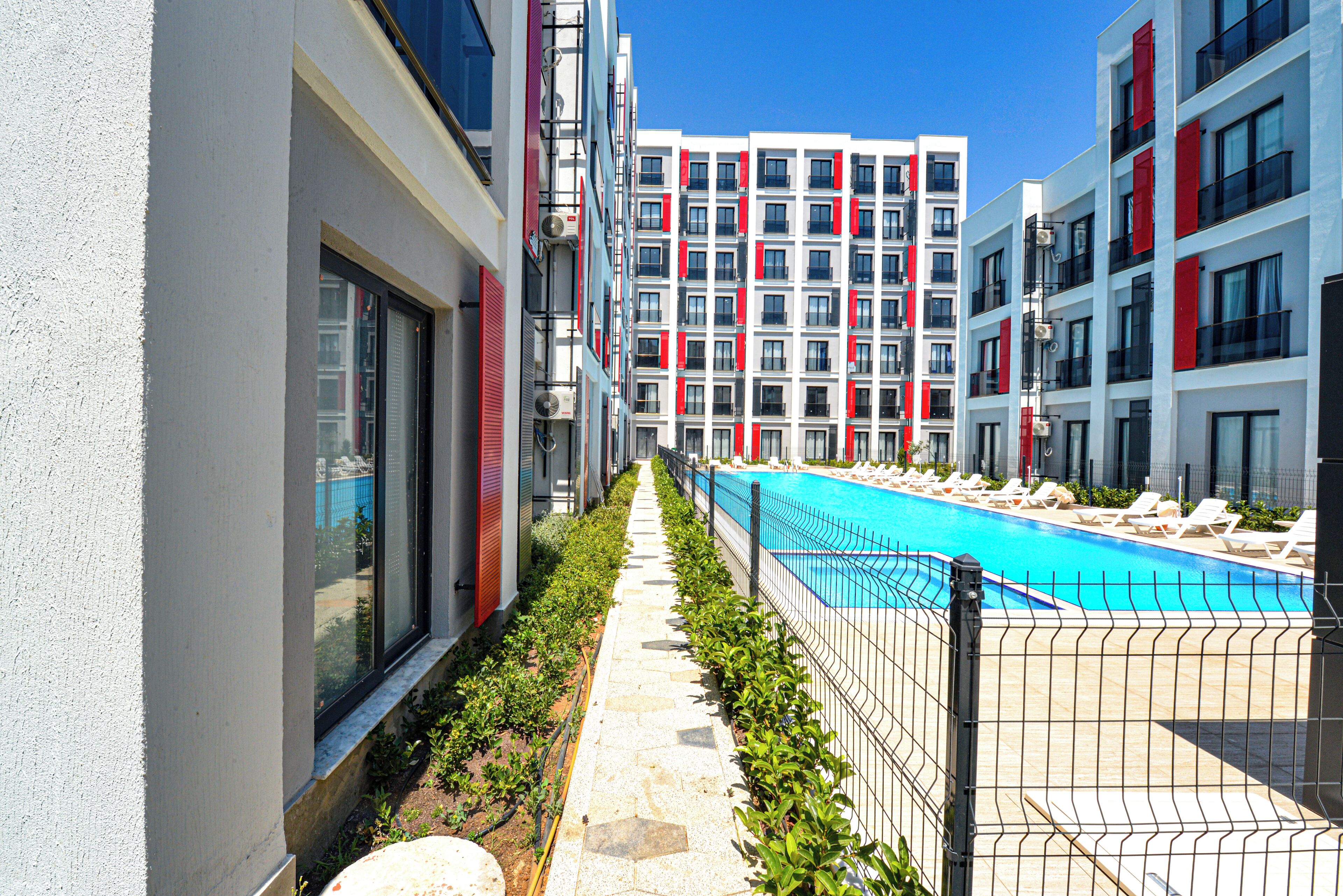A modern hotel with a swimming pool, a covered walkway, and a view of the pool area.