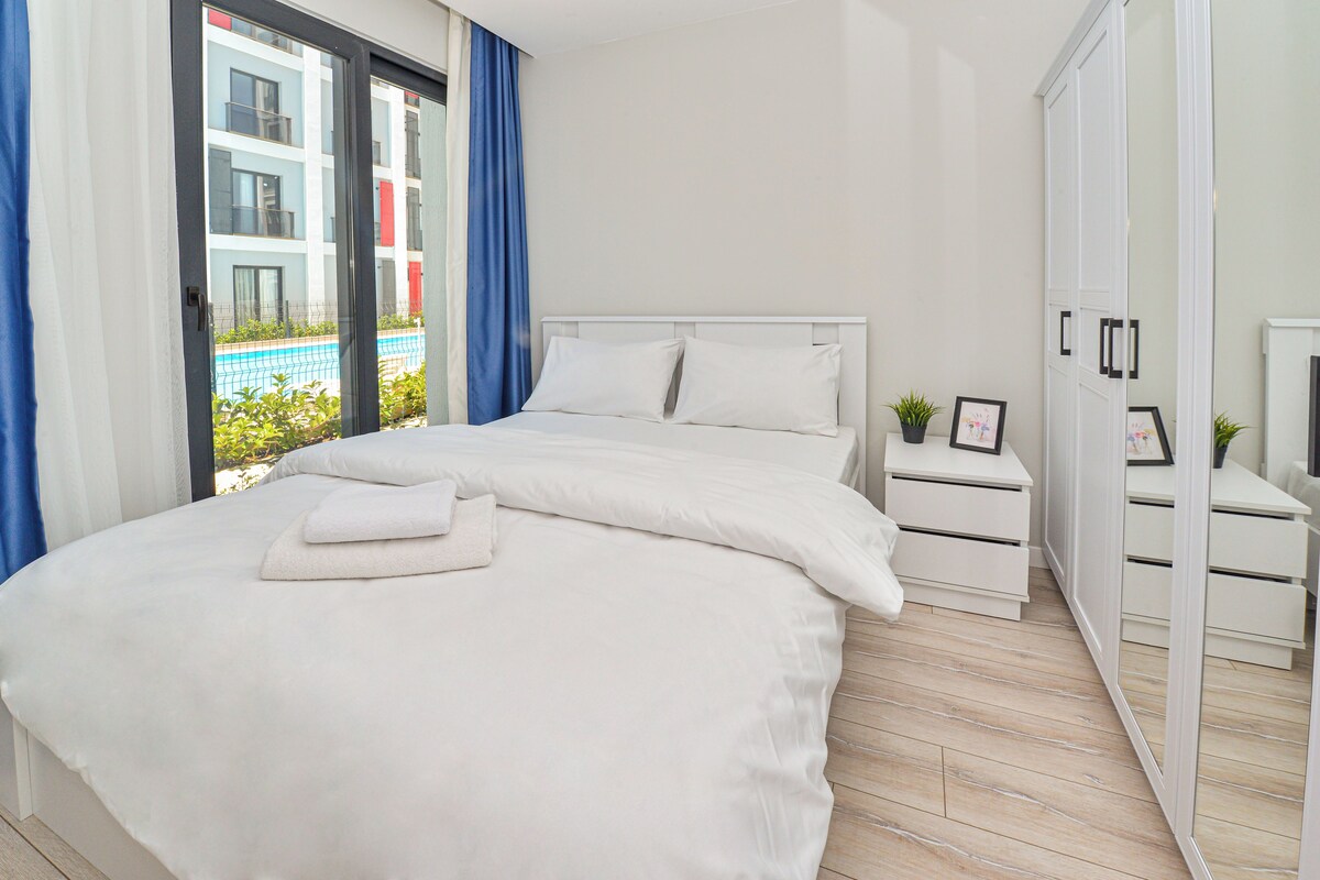 Un dormitorio con cama, mesita de noche, armario y vistas a una piscina.