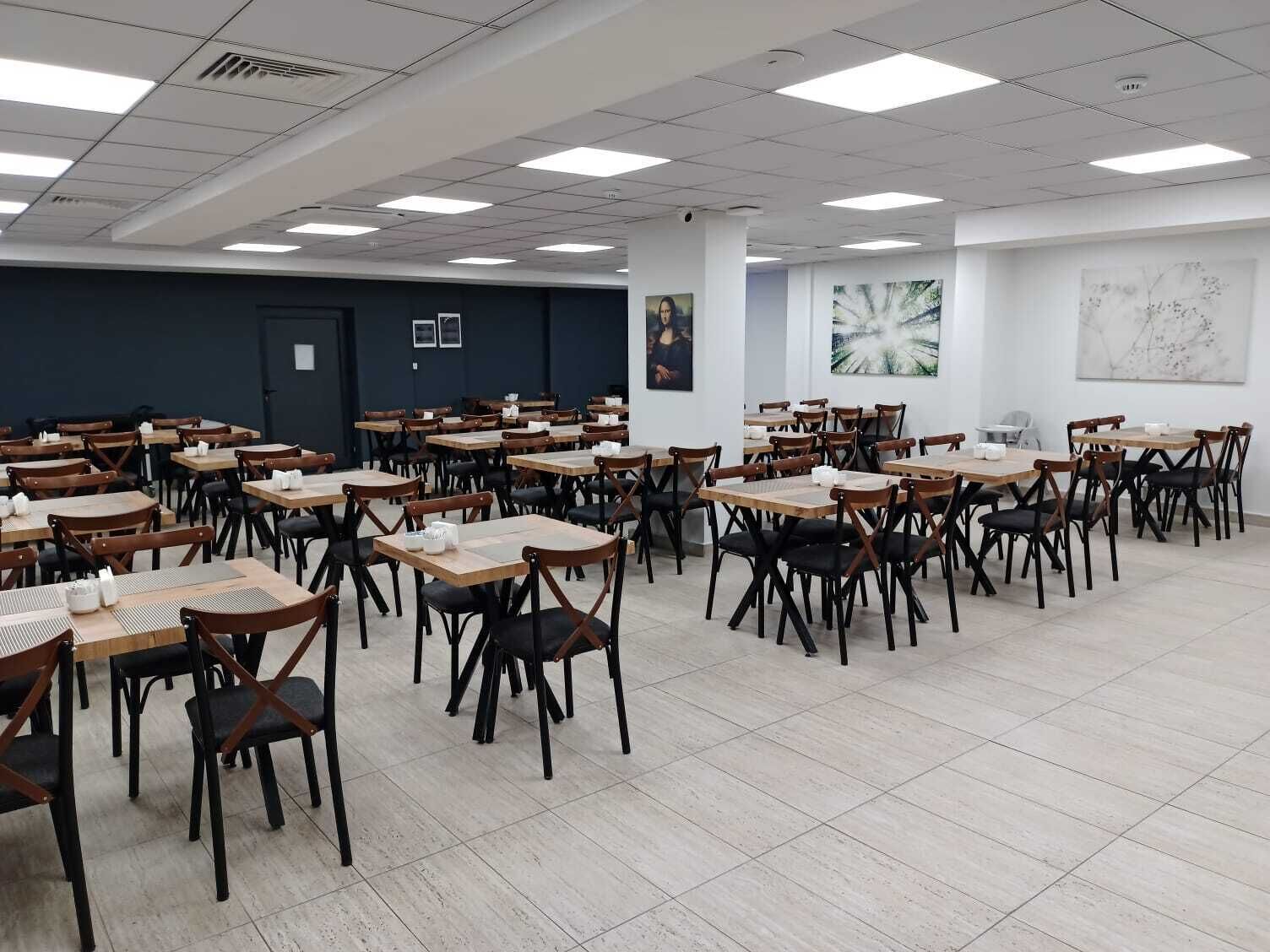 Une salle de conférence spacieuse, dotée de plusieurs tables et chaises, de murs blancs et d’un éclairage au plafond.