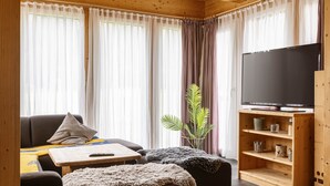 Ein gemütliches Wohnzimmer mit einer Couch, einem Couchtisch, einem Fernseher und einer Pflanze.
