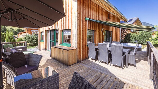 Een terras buiten met houten meubels en een bar.