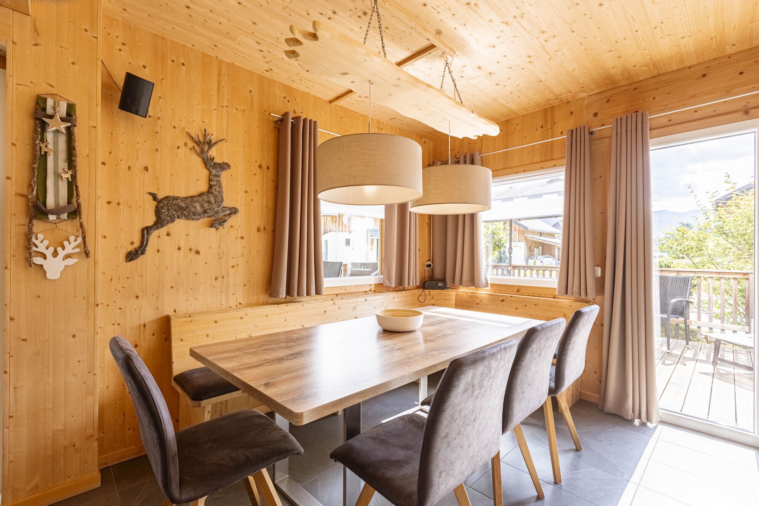 Un interno in legno con un tavolo da pranzo, sedie e un'ampia finestra.