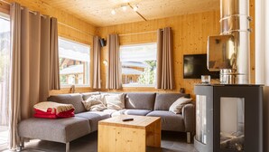 Een gezellige woonkamer met een hoekbank, een houten bijzettafeltje en een moderne open haard.