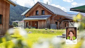 Ein Holzhaus mit geneigtem Dach, einer Veranda und einer sichtbaren Tür.