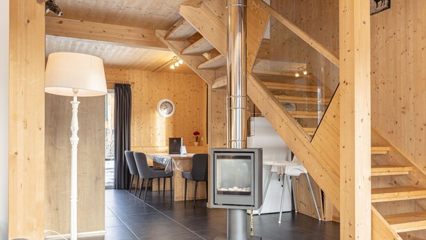 Ein Holzinnenraum mit Kamin, Essbereich und Treppe.