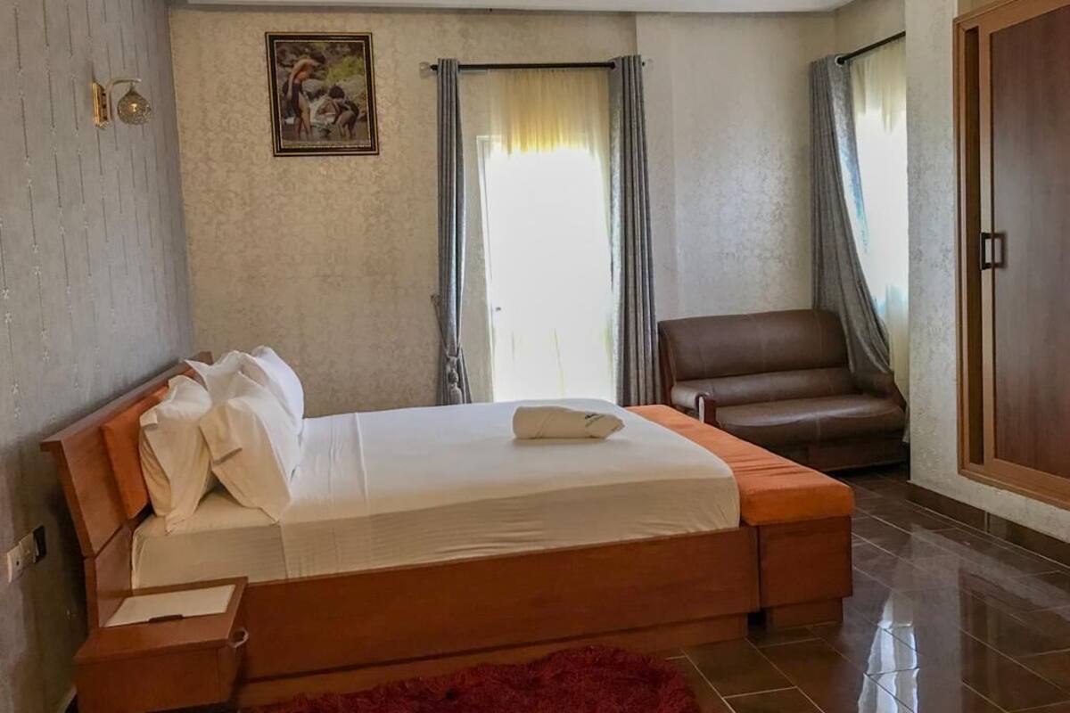 A bedroom with a bed, a chair, and a wardrobe.