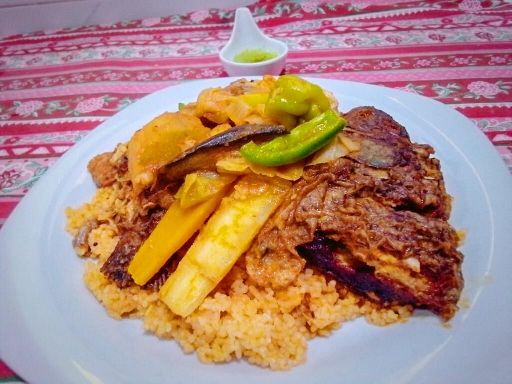 A plate of food with rice, meat, and vegetables on a tablecloth.