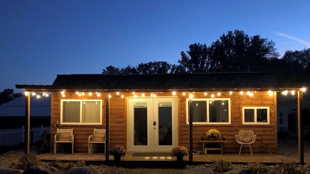 A wooden cabin with a porch, two windows, and a door.