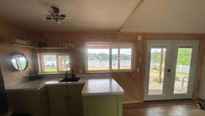 A kitchen with a large island, a window with a view of a lake, and a sliding glass door leading to a deck.