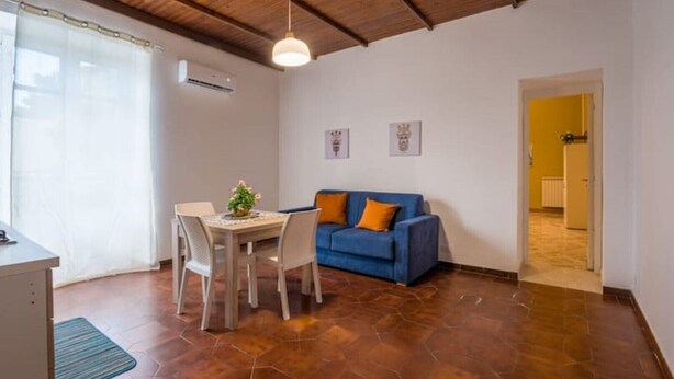 Una habitación con una mesa de comedor, sillas, un sofá azul y un ventilador de techo.