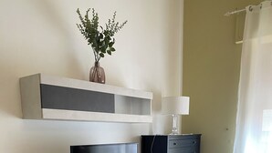 Una sala de estar moderna con un televisor de pantalla plana, una mesa de centro blanca y un piso de baldosas de piedra.