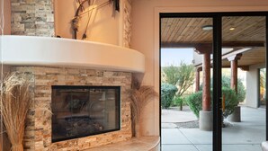 A stone fireplace with a glass door, a stone bench, and a view of the outdoor patio area. - Desert Oasis | TROON NORTH | Golf | Heated Pool (Scottsdale)
