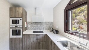 A modern kitchen with built-in appliances, a window with a view, and a tiled backsplash. - La Manga Club Los Altos Villa 367 (Atamaría)