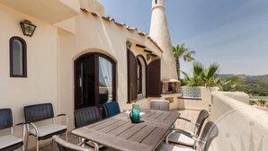 An outdoor patio with a table and chairs, a decorative lamp, and a view of the landscape. - La Manga Club Los Altos Villa 367 (Atamaría)