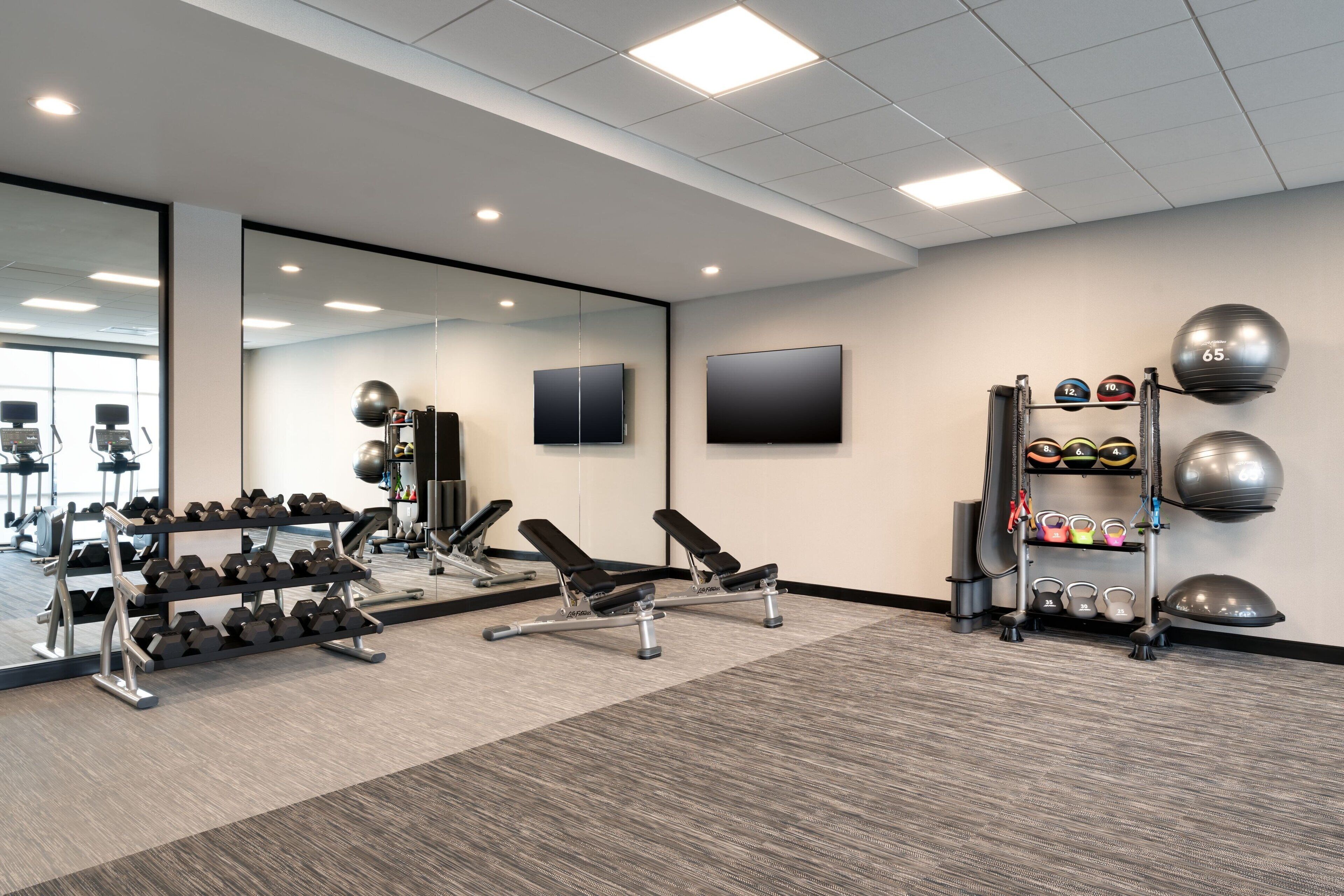 Un gimnasio con equipo de ejercicio, un espejo y una televisión.