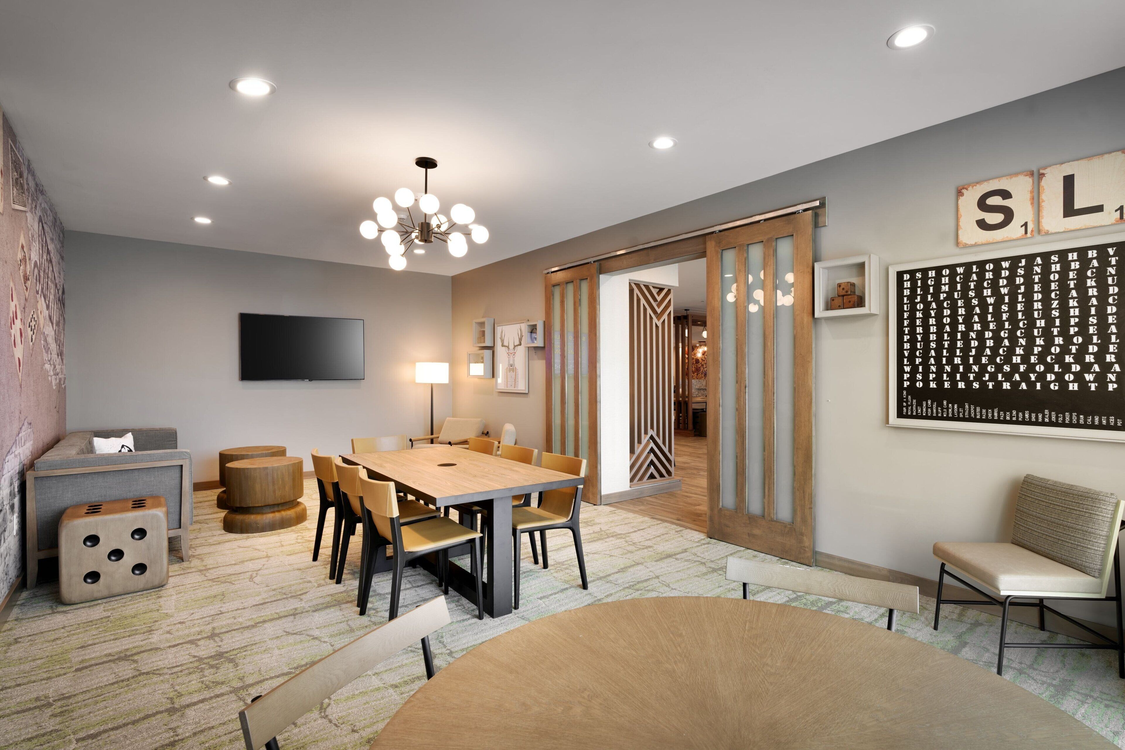 A modern living room with a dining area, a sofa, a coffee table, and a TV mounted on the wall.