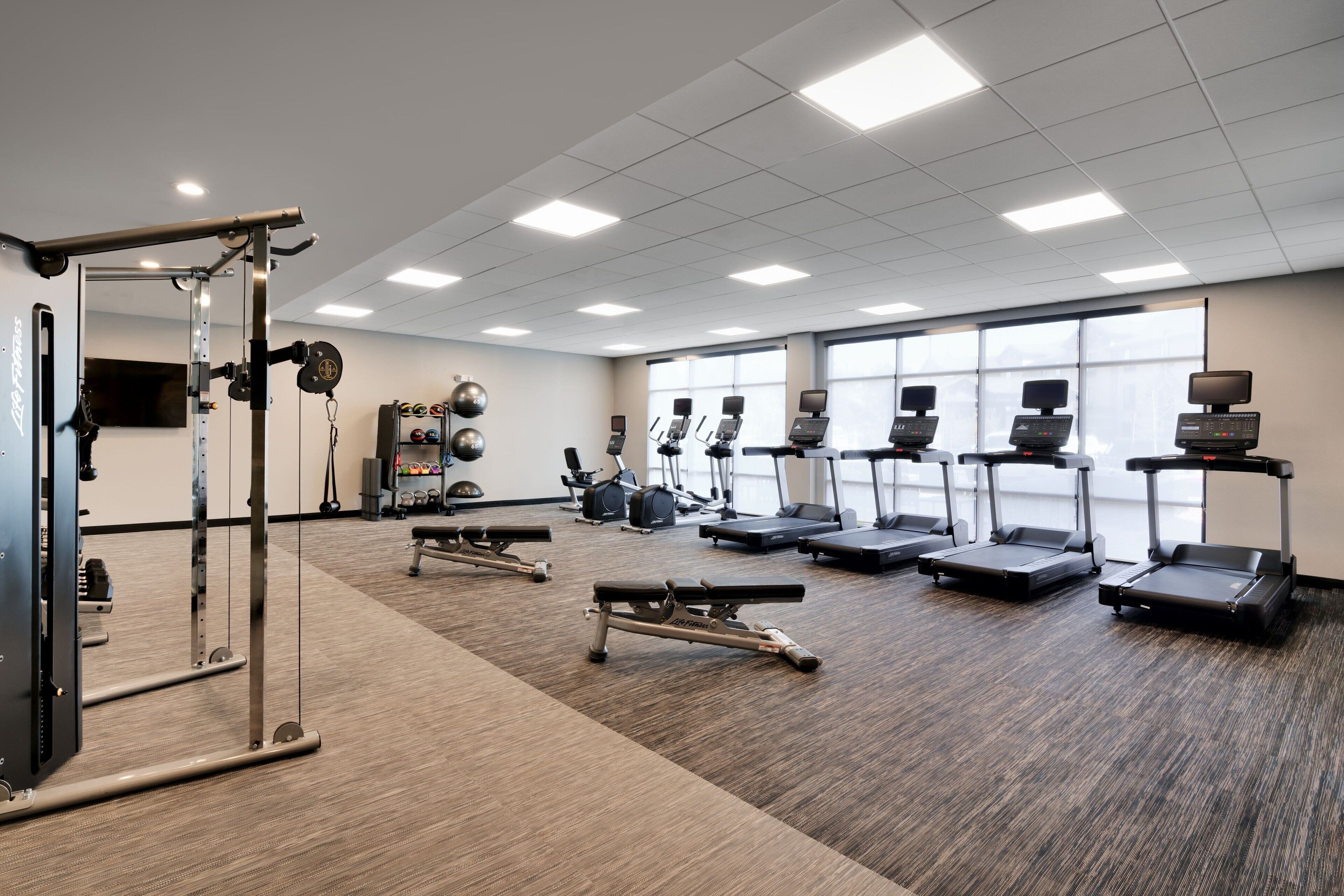 Uma academia com esteiras, elípticos e equipamentos de musculação.