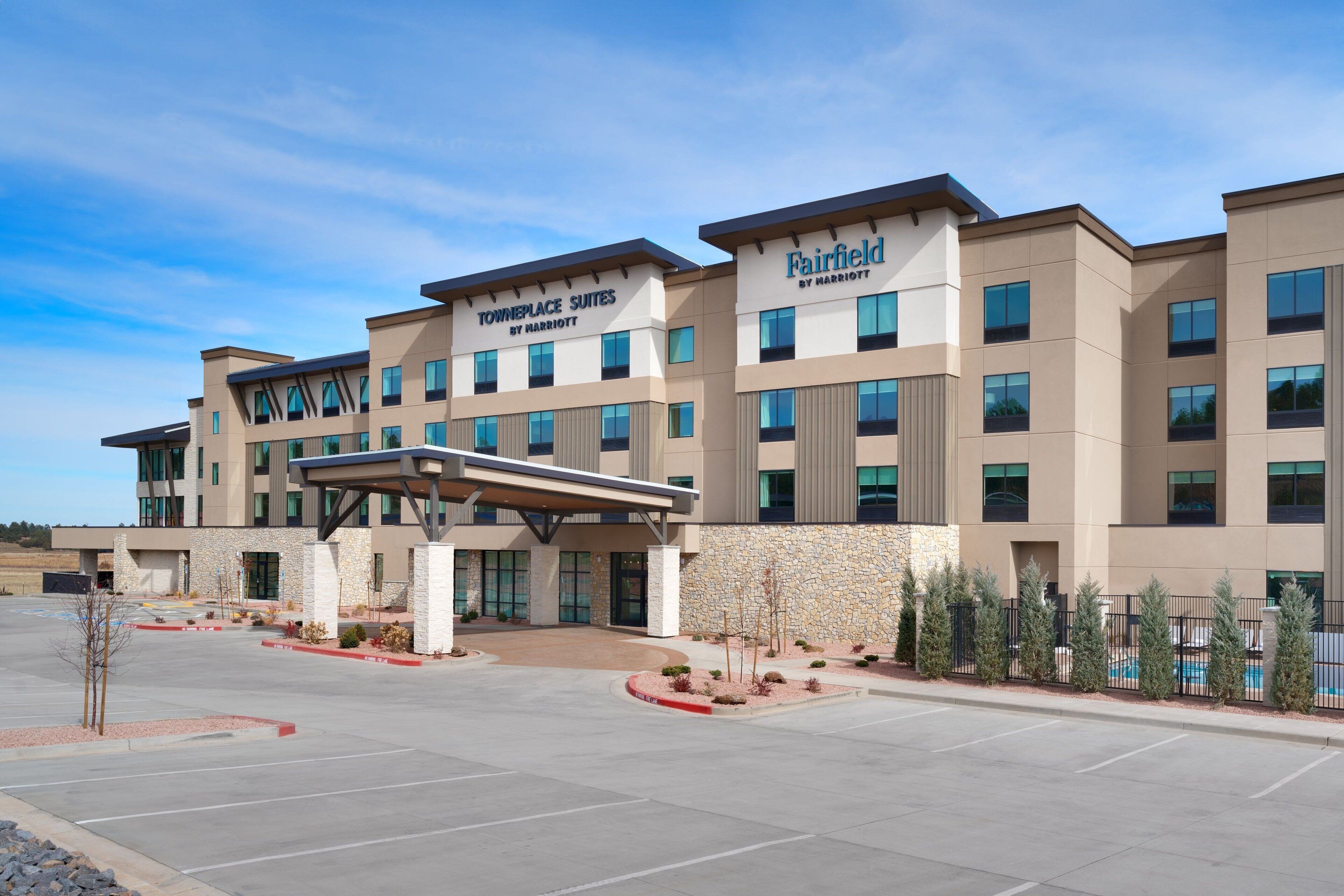 A multi-story hotel with a modern design, featuring a covered entrance and a swimming pool area.