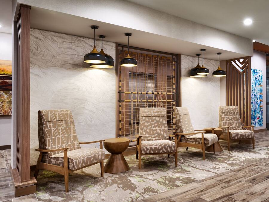 A lobby with four armchairs, a wooden coffee table, and pendant lighting.