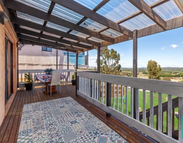 Relax in a serene outdoor space with a deck, rug, and breathtaking views of the surrounding green landscape.