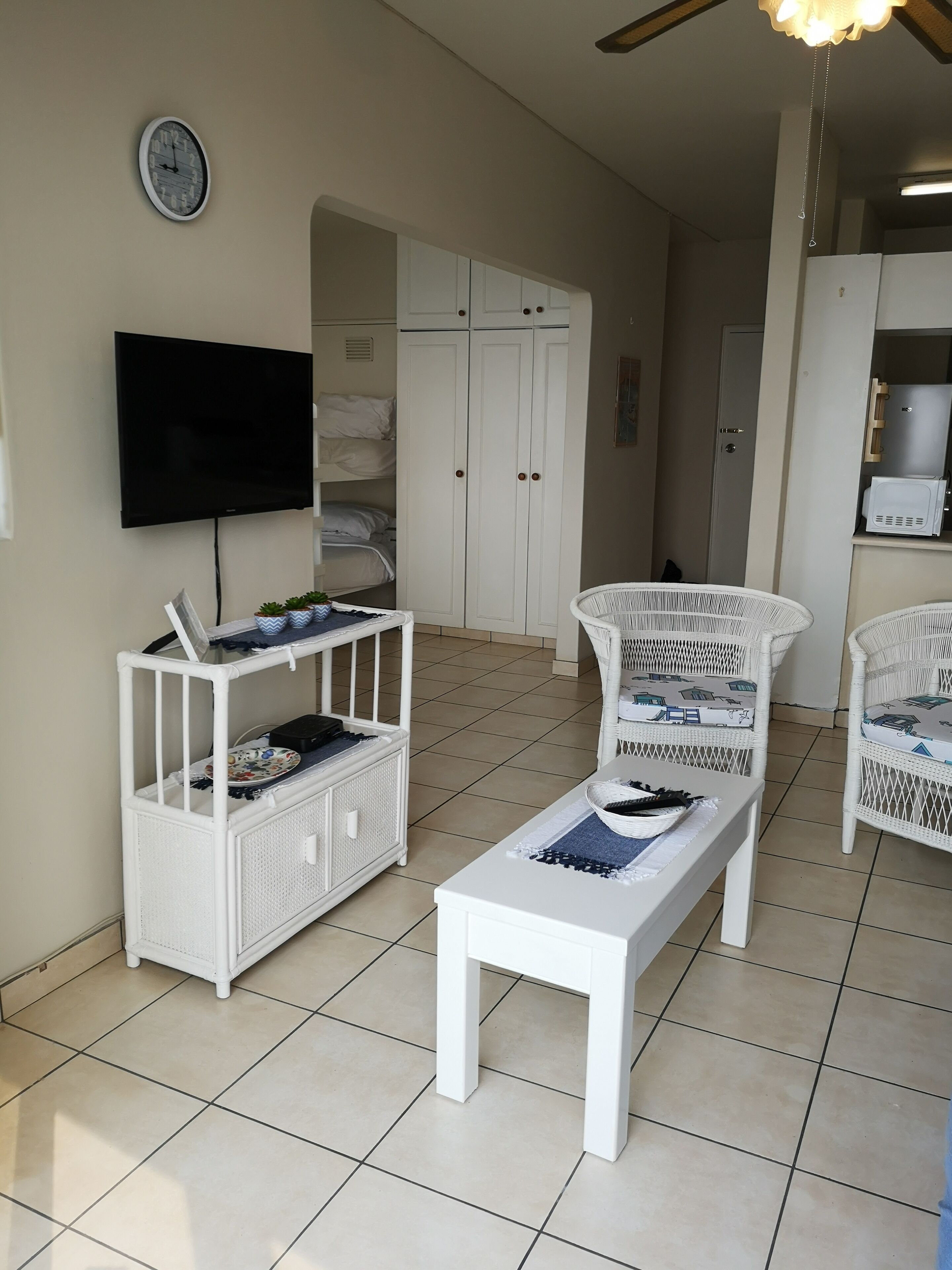 A living room with a white TV, white furniture, a white bench, and a white wardrobe.
