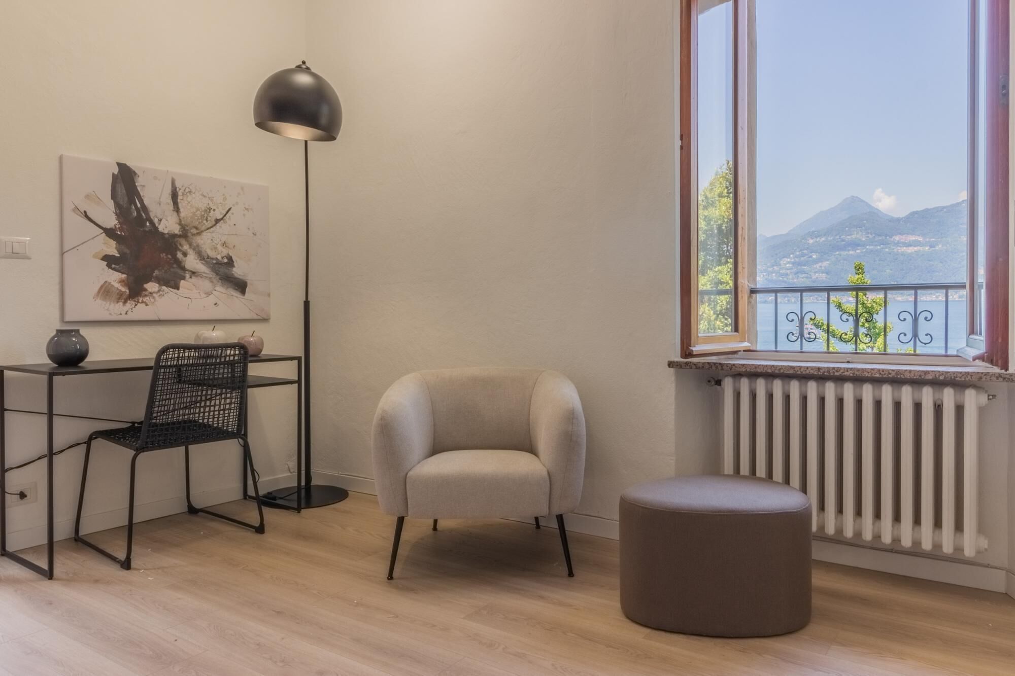 Een moderne kamer met uitzicht op een berg, een stoel, een tafel met een vaas en een vloerlamp.