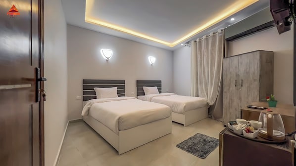 A hotel room with two beds, a desk with a coffee maker, and a wardrobe. - pyramids tower view inn (Giza)