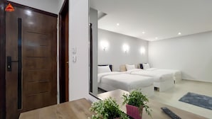 A modern hotel room with two beds, a wooden desk, and a potted plant. - pyramids tower view inn (Giza)